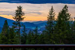 Experience breathtaking sunset views from this stunning property, nestled amidst lush evergreen trees.