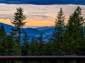 Experience breathtaking sunset views from this stunning property, nestled amidst lush evergreen trees.