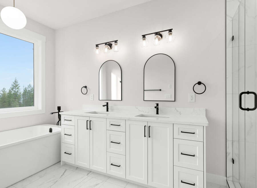 Experience modern luxury in this stunning bathroom featuring a freestanding soaking tub and a spacious double vanity with sleek black fixtures.