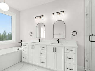 Experience modern luxury in this stunning bathroom featuring a freestanding soaking tub and a spacious double vanity with sleek black fixtures.