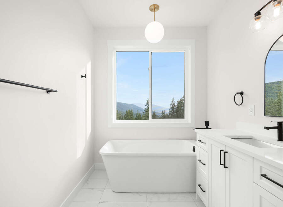 Experience serene living in this stunning bathroom featuring a luxurious freestanding bathtub with a breathtaking mountain view.