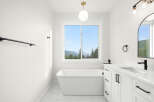 Experience serene living in this stunning bathroom featuring a luxurious freestanding bathtub with a breathtaking mountain view.
