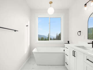 Experience serene living in this stunning bathroom featuring a luxurious freestanding bathtub with a breathtaking mountain view.