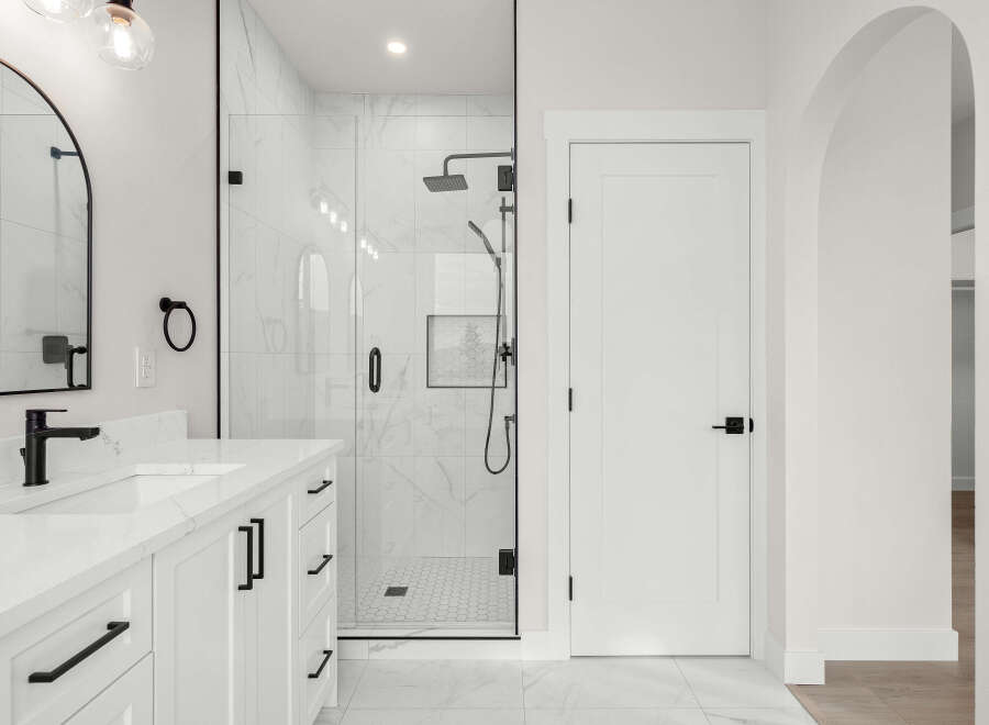Experience modern luxury in this stunning bathroom featuring a sleek double vanity with quartz countertops and black hardware.
