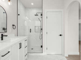 Experience modern luxury in this stunning bathroom featuring a sleek double vanity with quartz countertops and black hardware.