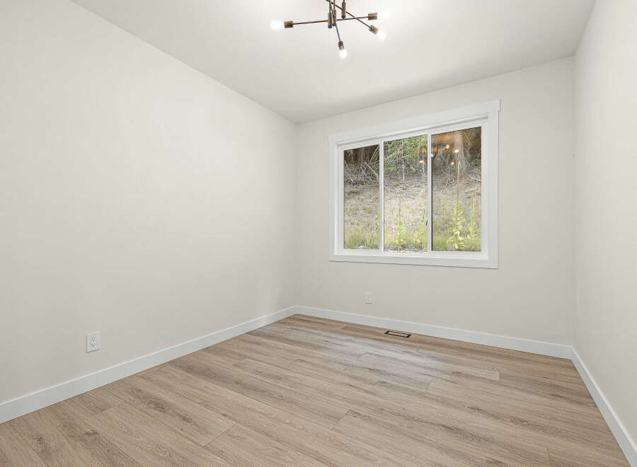 This empty room features a large sliding window offering a view of the natural landscape.