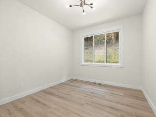This empty room features a large sliding window offering a view of the natural landscape.