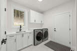 Discover this modern laundry room featuring sleek white cabinetry and a convenient undermount sink with a black faucet.