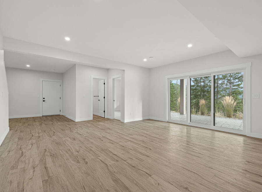 Step into this bright and airy finished basement, featuring a spacious open-concept living area with elegant wood-look flooring.