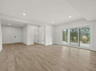 Step into this bright and airy finished basement, featuring a spacious open-concept living area with elegant wood-look flooring.