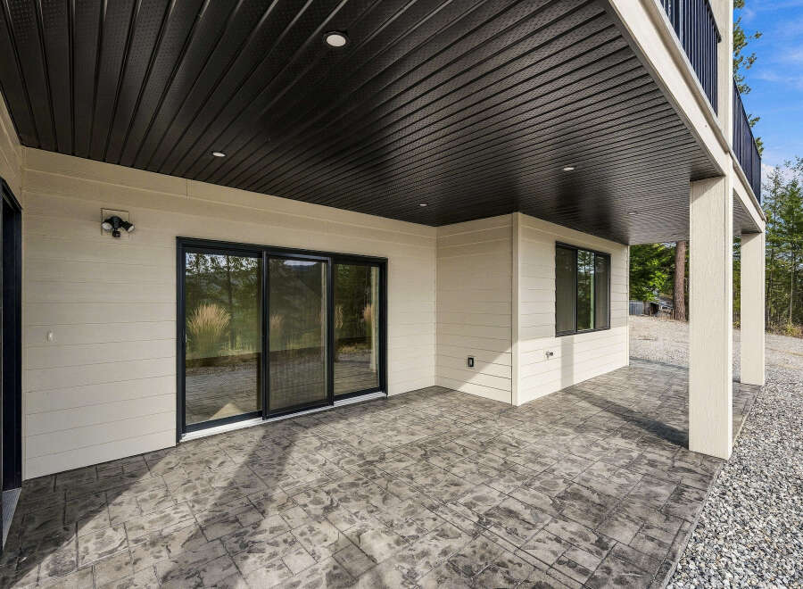 Enjoy the outdoors from this covered patio featuring a stamped concrete floor and a sleek black ceiling with recessed lighting.