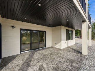 Enjoy the outdoors from this covered patio featuring a stamped concrete floor and a sleek black ceiling with recessed lighting.