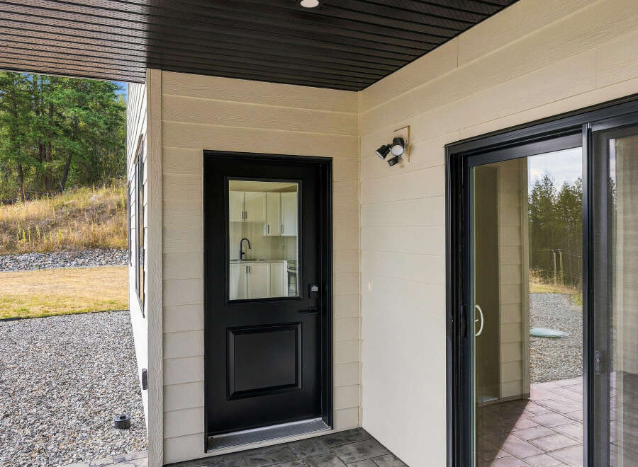 This property features a modern exterior with a black-trimmed glass door and a sliding glass door leading to an outdoor space.