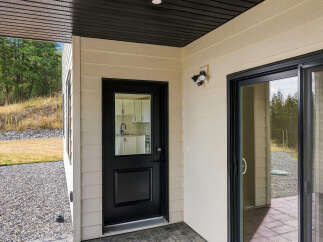 This property features a modern exterior with a black-trimmed glass door and a sliding glass door leading to an outdoor space.
