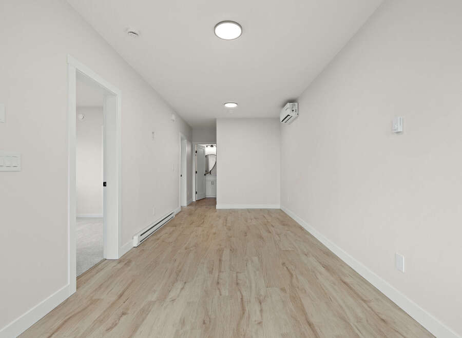 Step into this bright and airy hallway, featuring modern light wood laminate flooring and crisp white walls.
