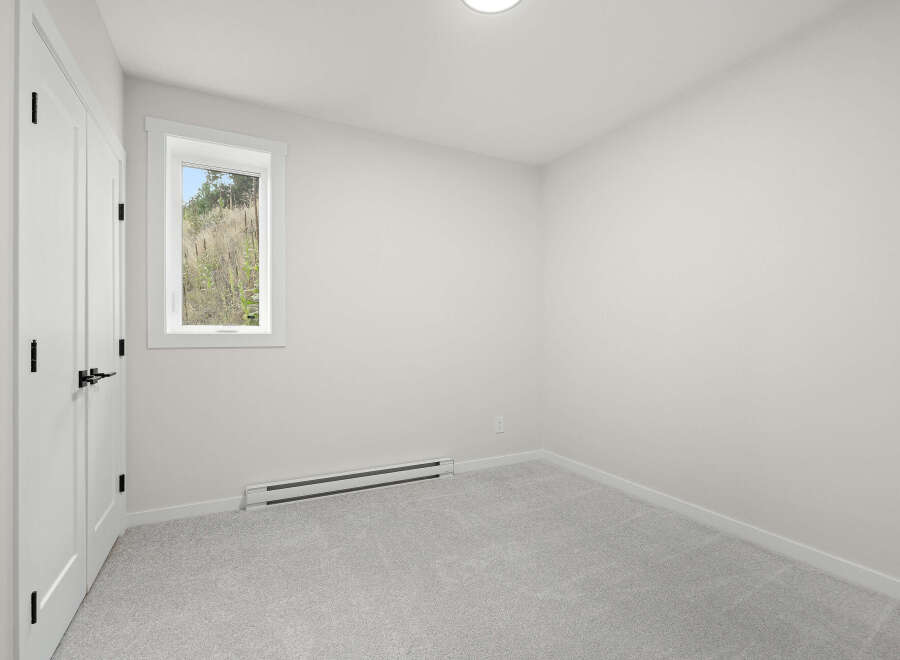 This bright and airy bedroom features a large window offering scenic views of the outdoors.