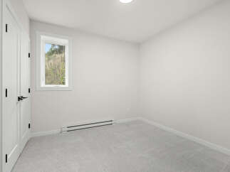 This bright and airy bedroom features a large window offering scenic views of the outdoors.
