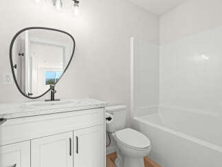 This modern bathroom features a sleek white vanity with a marble countertop, complemented by a stylish black-framed mirror.