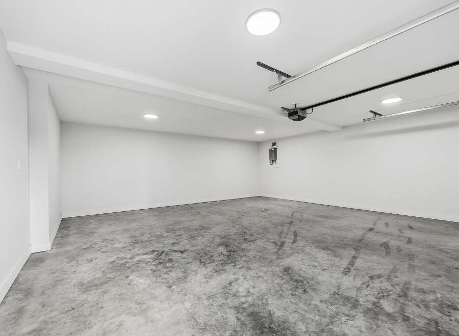 This spacious garage offers a clean and modern aesthetic with its polished concrete floors and bright white walls.
