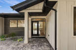 Experience modern living with this stunning home featuring a sleek entryway with a glass-paneled door and large windows.