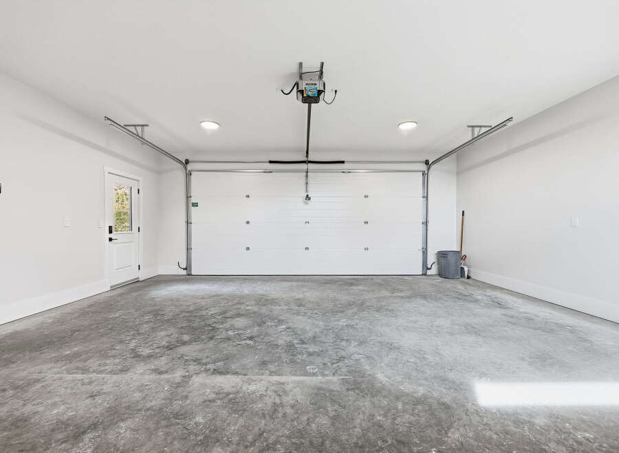 Step into this spacious and clean garage, featuring a modern white overhead door and a convenient side door for easy access.