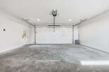 Step into this spacious and clean garage, featuring a modern white overhead door and a convenient side door for easy access.