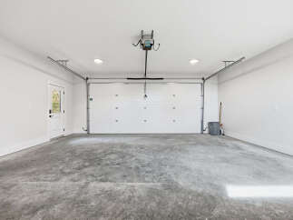 Step into this spacious and clean garage, featuring a modern white overhead door and a convenient side door for easy access.