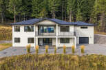 This modern two-story home boasts a sleek white exterior set against a backdrop of lush green pine trees.