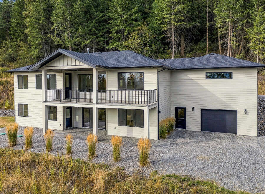 Discover this stunning modern home nestled against a backdrop of lush evergreen trees.