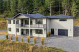 Discover this stunning modern home nestled against a backdrop of lush evergreen trees.