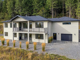 Discover this stunning modern home nestled against a backdrop of lush evergreen trees.