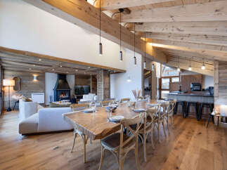 Experience luxury mountain living in this stunning chalet featuring a grand open-plan living and dining area with a cozy fireplace and exposed wooden beams.