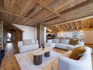 Experience luxury mountain living in this stunning chalet, featuring a spacious open-plan living area with a modern sectional sofa and a unique oval coffee table.
