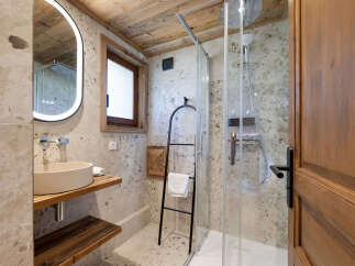 Experience luxury in this modern bathroom featuring a sleek glass-enclosed shower with a rainfall showerhead and convenient shelving for toiletries.