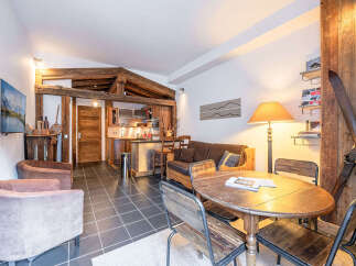 Experience cozy mountain living in this charming apartment, featuring exposed wooden beams and a rustic aesthetic.