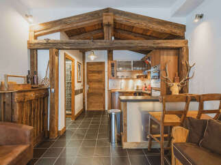 Experience rustic charm in this mountain retreat, featuring exposed wooden beams and a cozy kitchen area perfect for preparing meals after a day of adventure.