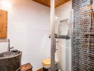This bathroom features a unique stone vessel sink paired with a modern chrome faucet, complemented by a rustic wooden medicine cabinet.