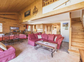 Experience rustic charm in this inviting living space, featuring a cozy red sectional sofa and a traditional dining area with a checkered tablecloth.