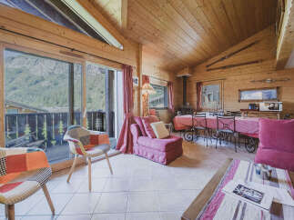 Experience cozy mountain living in this charming wooden chalet, featuring a spacious living and dining area with a picturesque view of the surrounding landscape.