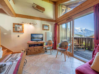 Experience breathtaking mountain views from this charming living area, featuring a cozy seating arrangement and a television for entertainment.