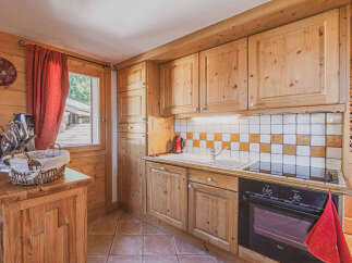 Charming wooden kitchen featuring custom cabinetry and a tiled backsplash.