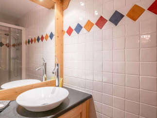 This charming bathroom features a modern vessel sink atop a dark countertop, complemented by sleek chrome faucets.