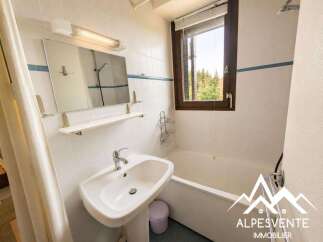 This charming bathroom features a clean white tiled interior, a spacious bathtub, and a modern vanity with a large mirror.