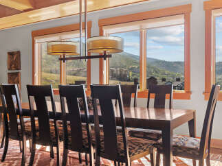 Experience breathtaking mountain views from this elegant dining room, featuring a large wooden table and chairs perfect for family gatherings.