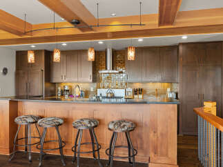 Experience luxury in this stunning kitchen featuring rich wood cabinetry and a gleaming metallic backsplash.