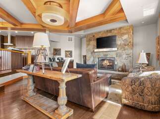 Experience rustic elegance in this stunning living room, featuring a magnificent stone fireplace and exposed wooden beams that add warmth and character.