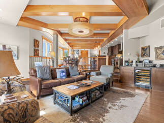 Experience rustic elegance in this spacious living area, featuring a rich leather sofa, a unique antler lamp, and a striking cowhide rug.
