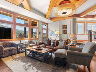 Experience luxury mountain living in this stunning great room, featuring a rich leather sofa, comfortable armchairs, and a rustic coffee table perfect for gatherings.