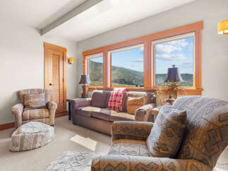 Experience breathtaking mountain views from this cozy living room, featuring a comfortable sofa and armchairs perfect for relaxation.