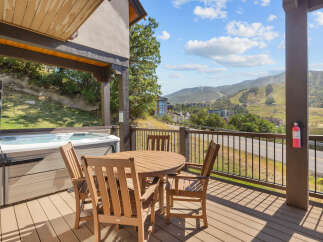 Enjoy breathtaking mountain views from this stunning deck, complete with a relaxing hot tub and a charming outdoor dining set.